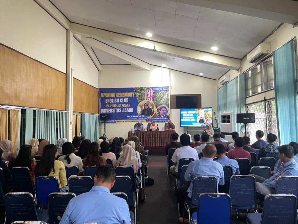 Students and library staff face the opening-ceremony stage in the Universitas Jambi Library auditorium